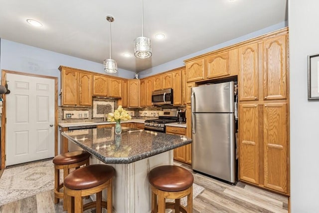 226 N Main St Unit 6, Walworth, WI 53184 - kitchen featuring appliances with stainless steel finishes, light wood finished floors, a kitchen breakfast bar, backsplash, and a center island