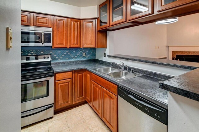 7102 Flagship Dr Unit 8, Madison, WI 53719 - kitchen with appliances with stainless steel finishes, a sink, dark countertops, brown cabinetry, and decorative backsplash