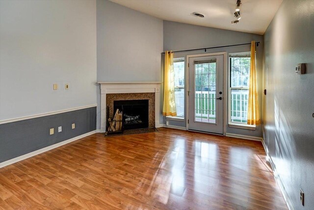 7102 Flagship Dr Unit 8, Madison, WI 53719 - unfurnished living room featuring lofted ceiling, wood finished floors, a fireplace with flush hearth, and baseboards