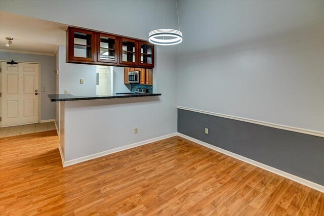 7102 Flagship Dr Unit 8, Madison, WI 53719 - empty room with crown molding, light wood finished floors, baseboards, and a chandelier