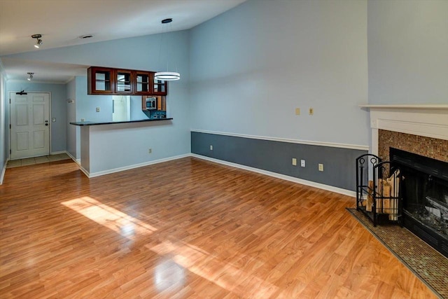 7102 Flagship Dr Unit 8, Madison, WI 53719 - unfurnished living room featuring lofted ceiling, wood finished floors, a premium fireplace, and baseboards