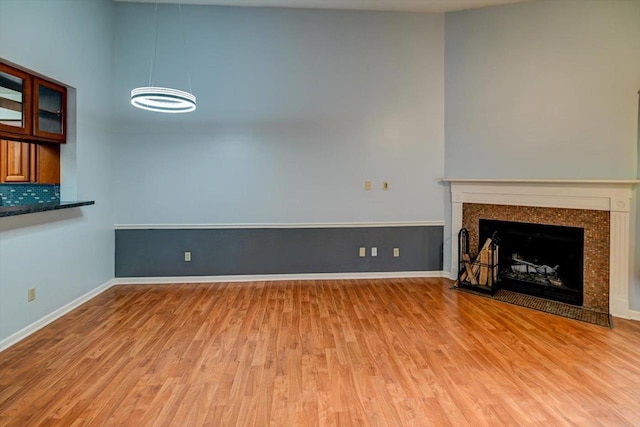 7102 Flagship Dr Unit 8, Madison, WI 53719 - unfurnished living room with light wood-style flooring, a chandelier, a fireplace with flush hearth, and baseboards