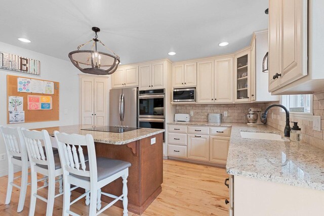 2074 Sandy Springs Rd, De Pere, WI 54115 - kitchen with stainless steel appliances, a sink, a breakfast bar, tasteful backsplash, and light stone countertops