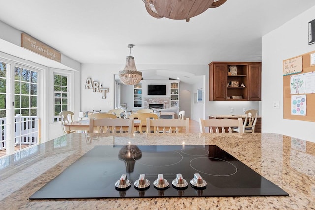 2074 Sandy Springs Rd, De Pere, WI 54115 - kitchen with black electric stovetop, a fireplace, light stone counters, open shelves, and pendant lighting