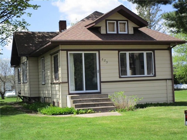 823 German St, Hawkins, WI 54530 - view of front of home featuring entry steps, a chimney, roof with shingles, and a front lawn