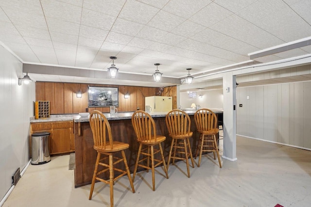 4901 Ralph Cir, Madison, WI 53714 - bar with finished concrete floors, freestanding refrigerator, wood walls, baseboards, and decorative light fixtures