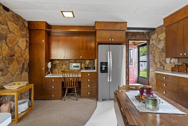 kitchen featuring stainless steel refrigerator with ice dispenser, light countertops, and brown cabinets