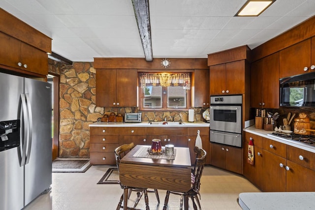 kitchen with stainless steel appliances, a warming drawer, light countertops, and light flooring