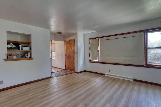 spare room with wood finished floors, baseboards, and built in shelves