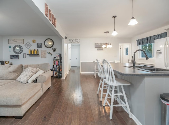 512 Conrad Ln, Beaver Dam, WI 53916 - kitchen with a kitchen bar, dark wood-type flooring, a sink, white fridge with ice dispenser, and hanging light fixtures