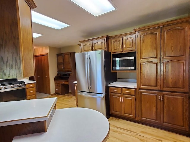 171 8th St, Clintonville, WI 54929 - kitchen featuring appliances with stainless steel finishes, light countertops, light wood-style floors, and brown cabinetry