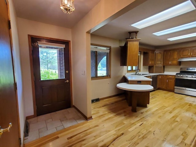 171 8th St, Clintonville, WI 54929 - kitchen featuring gas stove, light countertops, under cabinet range hood, a peninsula, and plenty of natural light