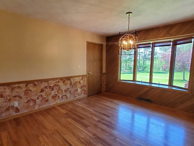 171 8th St, Clintonville, WI 54929 - unfurnished dining area with a chandelier, wood finished floors, baseboards, wainscoting, and wooden walls