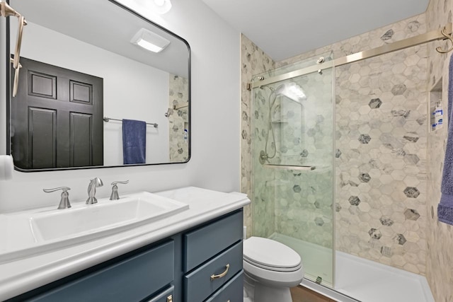 bathroom with a stall shower, toilet, and vanity
