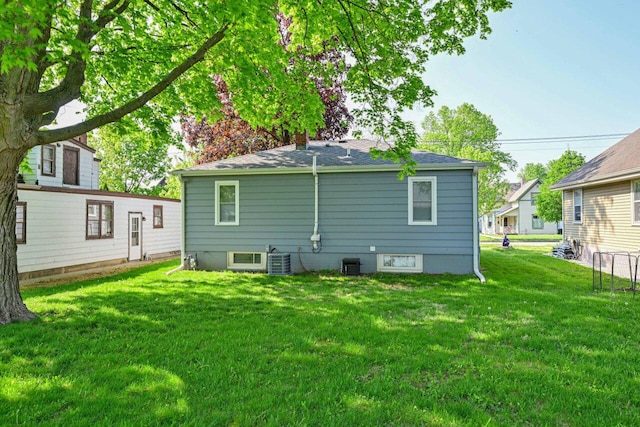 rear view of house featuring a yard, cooling unit, and a chimney