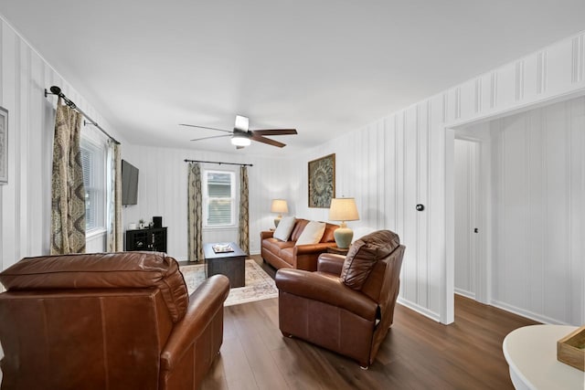 living room with dark wood-style floors, a ceiling fan, and baseboards