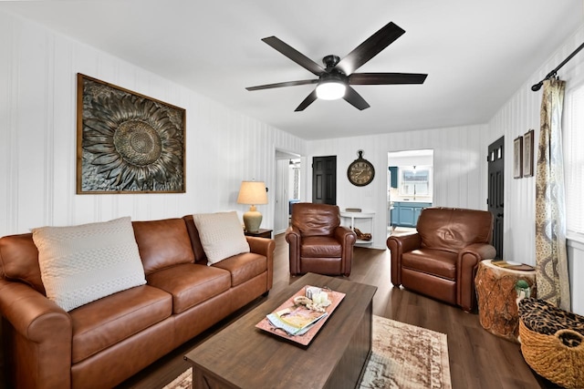 living room featuring wood finished floors, ceiling fan, and a decorative wall