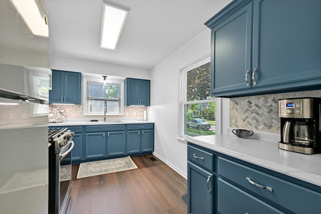 kitchen with blue cabinets, stainless steel gas range, a sink, light countertops, and tasteful backsplash