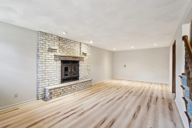 1714 Lewon Dr, Madison, WI 53711 - unfurnished living room with a brick fireplace, light wood finished floors, recessed lighting, baseboards, and stairs