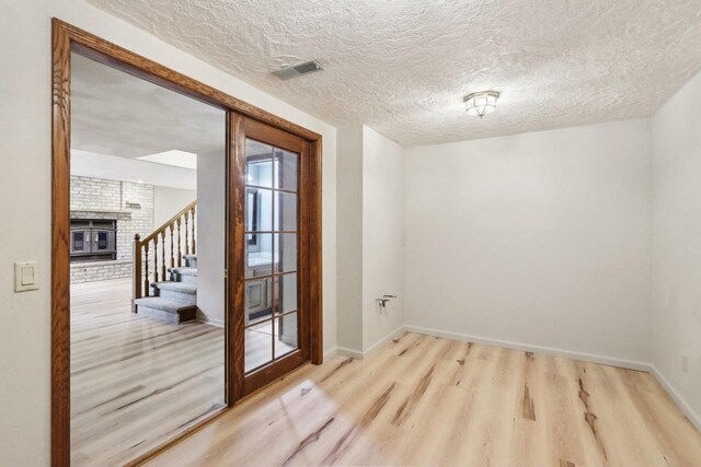 1714 Lewon Dr, Madison, WI 53711 - spare room with wood finished floors, stairway, a textured ceiling, baseboards, and a brick fireplace