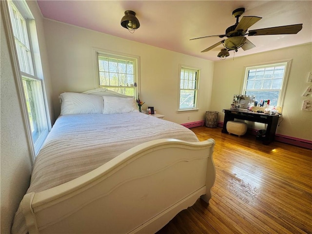 E6355 County Road D Dr, Colfax, WI 54730 - bedroom featuring multiple windows, wood finished floors, a baseboard heating unit, and baseboards