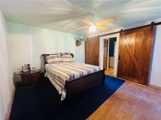 E6355 County Road D Dr, Colfax, WI 54730 - bedroom with a barn door, wood-type flooring, a ceiling fan, and baseboards