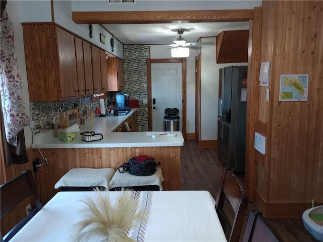 109 3rd St, Black River Falls, WI 54615 - kitchen with freestanding refrigerator, brown cabinets, decorative backsplash, ceiling fan, and a peninsula