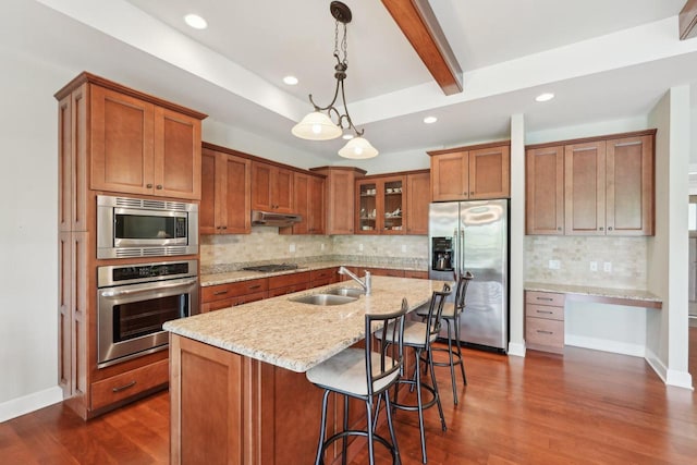2140 Prairie View Pt, Lake Geneva, WI 53147 - kitchen with stainless steel appliances, a sink, brown cabinetry, under cabinet range hood, and beamed ceiling
