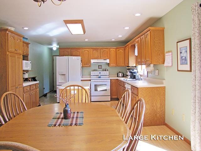 1060 Kamla Ct, Platteville, WI 53818 - kitchen featuring white appliances, extractor fan, light countertops, a sink, and recessed lighting