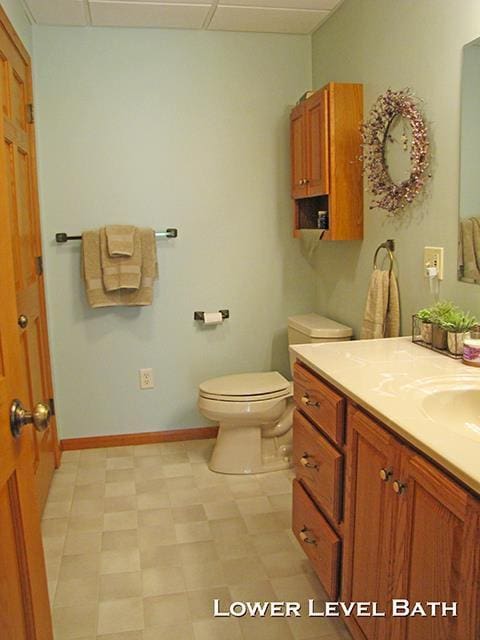 1060 Kamla Ct, Platteville, WI 53818 - bathroom with a paneled ceiling, baseboards, toilet, tile patterned floors, and vanity