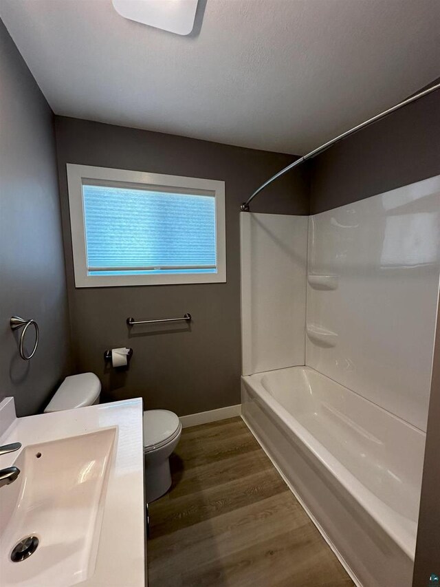 full bathroom with toilet, wood finished floors, baseboards, tub / shower combination, and vanity