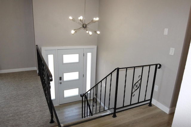 entryway featuring a chandelier, baseboards, wood finished floors, and a towering ceiling