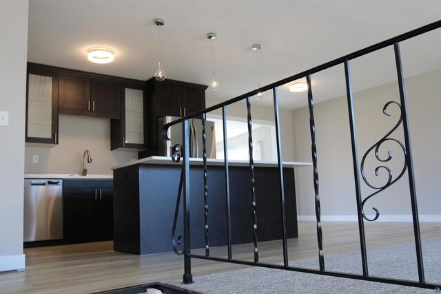 kitchen with appliances with stainless steel finishes, a sink, light wood-style floors, hanging light fixtures, and light countertops