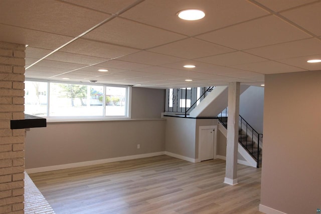 basement featuring baseboards, stairway, light wood-style flooring, recessed lighting, and a drop ceiling
