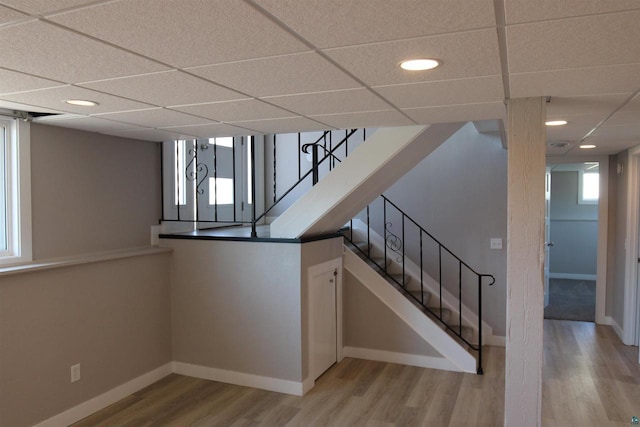 stairway featuring wood finished floors, a drop ceiling, baseboards, and recessed lighting