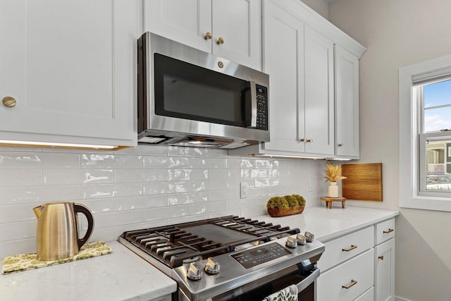 1801 Opus Ln Unit 101, Verona, WI 53593 - kitchen featuring stainless steel appliances, white cabinetry, decorative backsplash, light stone counters, and baseboards