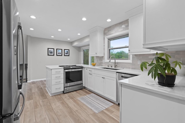 S58W22640 Glengarry Rd, Waukesha, WI 53189 - kitchen with stainless steel appliances, a sink, a peninsula, tasteful backsplash, and white cabinetry