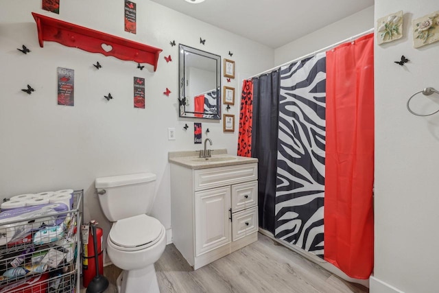 bathroom featuring wood finished floors, toilet, vanity, and a shower with shower curtain