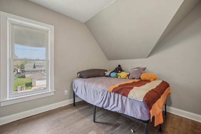 bedroom with vaulted ceiling, baseboards, and wood finished floors