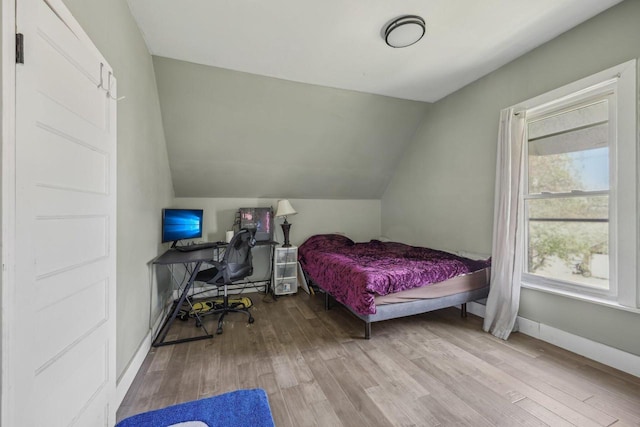 bedroom with lofted ceiling, wood finished floors, and baseboards