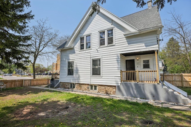 back of house featuring fence, a shingled roof, and a chimney