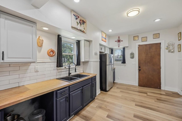kitchen with freestanding refrigerator, a sink, wooden counters, light wood-style flooring, and recessed lighting