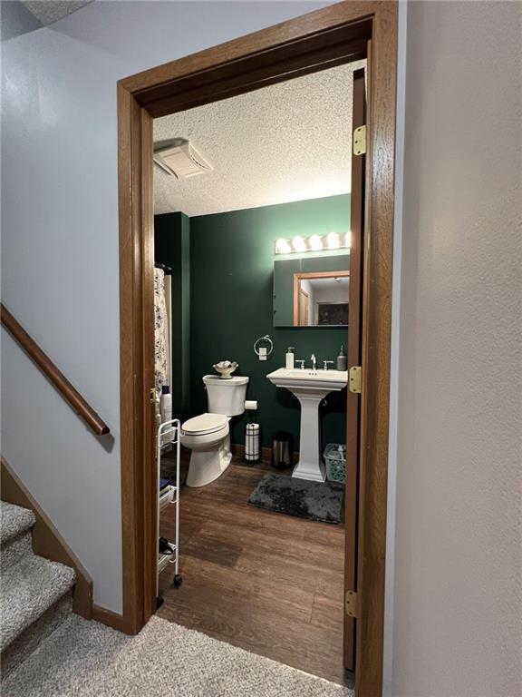 1123 Glades Dr, Altoona, WI 54720 - full bathroom with toilet, a textured ceiling, wood finished floors, a sink, and baseboards
