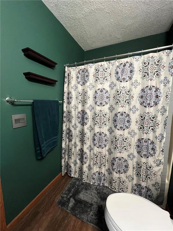 1123 Glades Dr, Altoona, WI 54720 - bathroom featuring wood finished floors, toilet, a textured ceiling, a shower with curtain, and baseboards