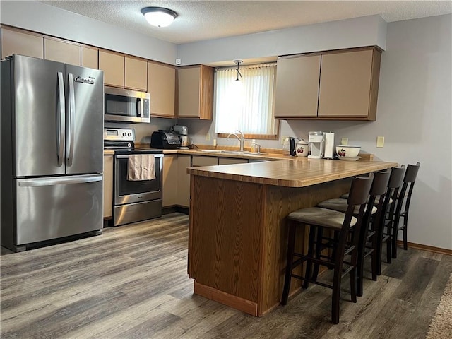 1123 Glades Dr, Altoona, WI 54720 - kitchen with appliances with stainless steel finishes, wood finished floors, a peninsula, a sink, and a textured ceiling