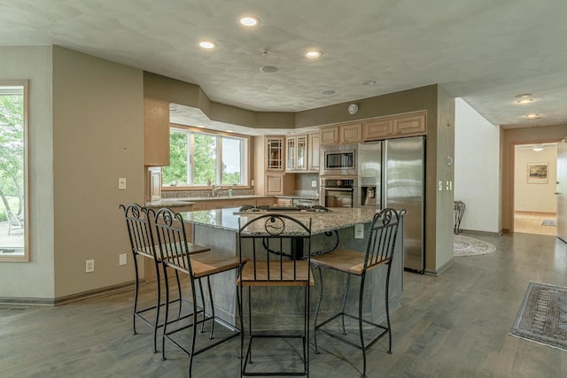 W6504 Klassy Rd, New Glarus, WI 53574 - kitchen with stainless steel appliances, a kitchen island, a breakfast bar area, light stone countertops, and light wood-style flooring