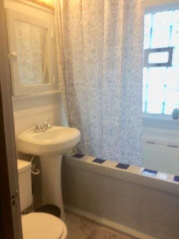 full bath featuring toilet and shower / bath combination with curtain