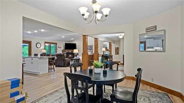 E3313 Jennifer Ln, Eau Claire, WI 54701 - dining space with a glass covered fireplace, ornate columns, light wood-type flooring, a chandelier, and baseboards