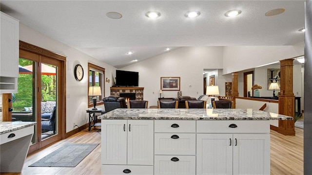 E3313 Jennifer Ln, Eau Claire, WI 54701 - kitchen with vaulted ceiling, a fireplace, open floor plan, light wood-type flooring, and white cabinets