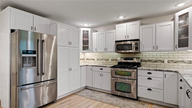 E3313 Jennifer Ln, Eau Claire, WI 54701 - kitchen with stainless steel appliances, light wood-type flooring, white cabinets, light stone countertops, and glass insert cabinets